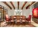 Elegant dining room featuring wood-beam ceilings, chandelier, and a long wood table with red upholstered chairs at 27903 N Agua Verde Dr, Rio Verde, AZ 85263