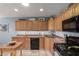 Traditional kitchen with wooden cabinetry, black appliances, and an island table at 3834 N 32Nd Pl, Phoenix, AZ 85018