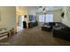 Spacious carpeted living room with a ceiling fan, large TV, comfortable seating, and a staircase visible at 671 E Colt Ct, Chandler, AZ 85225