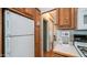 Well-lit kitchen featuring wood cabinetry, white appliances, and convenient access to storage areas at 711 Felspar Dr, Apache Junction, AZ 85119