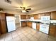 Well-lit kitchen with tile floor, plentiful cabinetry, and white appliances at 7754 W Mitchell Dr, Phoenix, AZ 85033