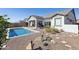 A private backyard featuring a sparkling pool, desert landscaping, and a covered patio with an outdoor fireplace at 8043 E Jaeger St, Mesa, AZ 85207