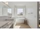 Bright bathroom featuring double sinks, a soaking tub, light wood flooring, and natural light at 8043 E Jaeger St, Mesa, AZ 85207