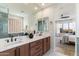 A modern bath boasts dual sinks, granite counters, wood cabinets, and a glass block shower at 11617 E Raintree Dr, Scottsdale, AZ 85255