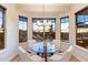 Bright breakfast nook features a glass table and scenic desert views from the surrounding bay windows at 11617 E Raintree Dr, Scottsdale, AZ 85255