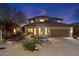 Stunning two-story home featuring desert landscaping, a tile roof, and a two-car garage, all beautifully illuminated at twilight at 11617 E Raintree Dr, Scottsdale, AZ 85255
