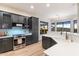 Stylish kitchen featuring sleek, dark cabinetry, stainless steel appliances, and a breakfast bar overlooking the living area at 11617 E Raintree Dr, Scottsdale, AZ 85255