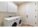Bright laundry room equipped with modern washer, dryer, and ample storage cabinets at 11617 E Raintree Dr, Scottsdale, AZ 85255