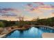 Tranquil pool featuring a small rock waterfall and desert landscaping against a sunset sky at 11617 E Raintree Dr, Scottsdale, AZ 85255