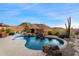 Backyard with a freeform pool, waterfall feature, and a view of the mountain in the distance at 11617 E Raintree Dr, Scottsdale, AZ 85255