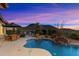 Inviting backyard pool featuring a rock waterfall with a beautiful pink and blue dusk sky at 11617 E Raintree Dr, Scottsdale, AZ 85255