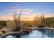 Picturesque pool with a rock waterfall feature, surrounded by lush landscaping and offering stunning sunset views at 11617 E Raintree Dr, Scottsdale, AZ 85255