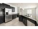 A spacious kitchen featuring dark cabinetry, stainless steel appliances, and a granite countertop island with a sink at 1170 E Taylor Trl, San Tan Valley, AZ 85143