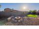 Backyard featuring rock landscaping, synthetic grass, a custom stone fire pit and a privacy wall at 15993 W Poinsettia Dr, Surprise, AZ 85379