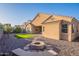 Inviting backyard with a cozy fire pit, artificial grass, and low-maintenance desert landscaping at 15993 W Poinsettia Dr, Surprise, AZ 85379