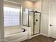 Bright bathroom showcasing a soaking tub, separate shower with glass enclosure, and wood look flooring at 15993 W Poinsettia Dr, Surprise, AZ 85379