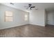 Expansive room showcasing wood floors, a ceiling fan, and three windows for natural light at 15993 W Poinsettia Dr, Surprise, AZ 85379