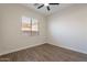 Empty bedroom featuring wood look flooring, a ceiling fan, and a large window at 15993 W Poinsettia Dr, Surprise, AZ 85379