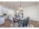 Open-concept dining area with a modern chandelier, gray table and chairs, and a view into the kitchen at 15993 W Poinsettia Dr, Surprise, AZ 85379