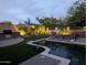 Backyard at dusk showcasing a pool with rock waterfall feature, an outdoor kitchen, and manicured landscaping at 1633 N Woodruff --, Mesa, AZ 85207