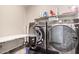 Laundry room featuring a front-load washer, dryer, shelving, and folding table at 17474 W Straight Arrow Ln, Surprise, AZ 85387