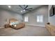 Large bedroom with neutral carpet, ceiling fan, windows with shutters, and a light wood dresser and nightstands at 20061 E Cherrywood Ct, Queen Creek, AZ 85142