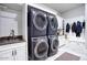 Modern laundry room with stacked washer/dryer, sink, storage, and bench with hooks for coats at 20061 E Cherrywood Ct, Queen Creek, AZ 85142