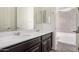 Bathroom with double sinks, dark wood vanity, and shower and tub in the background at 21255 W Ashland Ave, Buckeye, AZ 85396