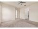 This bedroom has neutral carpeting, a ceiling fan, and a doorway with a view to another room at 21255 W Ashland Ave, Buckeye, AZ 85396
