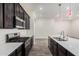 Modern kitchen featuring stainless steel appliances, a central island, and dark cabinetry, seamlessly connected to the living area at 21255 W Ashland Ave, Buckeye, AZ 85396
