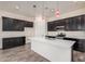 Modern kitchen featuring dark cabinetry, stainless steel appliances, a kitchen island, and stylish pendant lighting at 21255 W Ashland Ave, Buckeye, AZ 85396