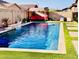 Backyard pool oasis featuring a waterfall feature, lush turf, and comfortable seating areas for relaxing and entertaining at 21255 W Ashland Ave, Buckeye, AZ 85396
