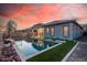 Backyard pool with artificial grass, patio, and grey home exterior at dusk at 21255 W Ashland Ave, Buckeye, AZ 85396