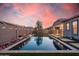Beautiful backyard pool with rock landscaping, string lights, and a pergola at sunset at 21255 W Ashland Ave, Buckeye, AZ 85396