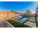 Backyard pool with rock landscaping, artificial grass, and light-colored patio tiles at 21255 W Ashland Ave, Buckeye, AZ 85396