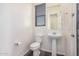 This powder room offers a pedestal sink, toilet, and window with modern fixtures at 21255 W Ashland Ave, Buckeye, AZ 85396