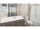 Bright bathroom featuring neutral cabinets, white sink, a tub/shower combo, and white toilet at 26635 W Covey Ln, Buckeye, AZ 85396