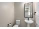 Powder room featuring a pedestal sink, toilet, and rectangle mirror at 26635 W Covey Ln, Buckeye, AZ 85396