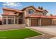A view of the home's front exterior features a green lawn, a desert-style gravel bed, and a three-car garage at 4129 E Nighthawk Way, Phoenix, AZ 85048