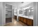 Bathroom with dual sinks, large mirrors, tile floor, and walk-in closet with sliding doors at 43646 W Elizabeth Ave, Maricopa, AZ 85138