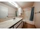 Bathroom with a single sink vanity, neutral countertop, and shower-tub combo with blue curtain at 4916 E Hopi St, Phoenix, AZ 85044