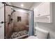 Modern bathroom with tiled walk-in shower, river rock floor, and built-in shelving, complemented by white storage cabinets at 4916 E Hopi St, Phoenix, AZ 85044