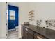 Modern bathroom with a sleek dark vanity, floating shelves, blue accent wall, and plenty of storage at 5650 S Feliz --, Mesa, AZ 85212
