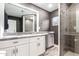 Modern bathroom with a double vanity, granite countertops, white cabinets, and a glass-enclosed shower at 6119 N 18Th Dr, Phoenix, AZ 85015