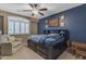 Bedroom with a blue accent wall, window with shutters, chair, and dark wood furniture at 8761 W Mary Ann Dr, Peoria, AZ 85382