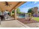 Inviting covered patio with ceiling fans, overlooking a pool with safety fence and meticulously landscaped backyard at 8761 W Mary Ann Dr, Peoria, AZ 85382