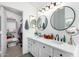 Well-lit bathroom with a double vanity, round mirrors, and walk-in closet access at 9922 E Onza Ave, Mesa, AZ 85212