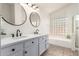 Renovated bathroom with dual sinks, white cabinetry, and decorative mirrors at 9922 E Onza Ave, Mesa, AZ 85212