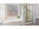 Bright bathroom featuring a soaking tub and a glass-enclosed shower with stylish tile and a block glass window at 9922 E Onza Ave, Mesa, AZ 85212