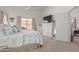 Well-lit primary bedroom with carpet floors, tv, dresser, leafy patterned linens, and ensuite access at 9922 E Onza Ave, Mesa, AZ 85212